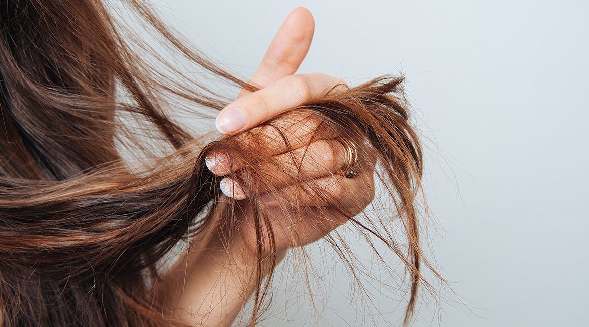 Frau streicht sich durch ihre braunen langen Haarsträhnen